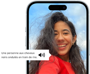 Un iPhone 15 affichant une annonce VoiceOver décrivant le contenu d’une photographie en ces termes : une personne aux cheveux noirs ondulés en train de rire
